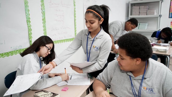 Nidhi Patel, an eighth-grader at Charter School of New Castle, passes out papers during class. She hopes to attend either Charter School of Wilmington or Conrad Schools of Science next year.