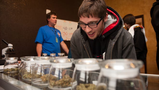 Tyler Williams of Blanchester, Ohio, selects marijuana strains to purchase Jan. 1, 2014, at the 3-D Denver Discrete Dispensary.