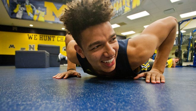 Michigan forward D.J. Wilson (5) stretches out on the mats before a practice session at Crisler Center in Ann Arbor, Mich., Friday, Oct. 2, 2015.