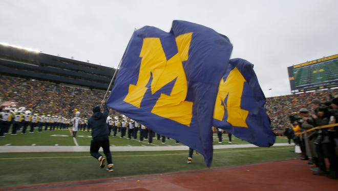 Michigan cheerleaders run on the field with large Block M flags before their football game against Ohio State on Saturday, November 28, 2015, in Ann Arbor.