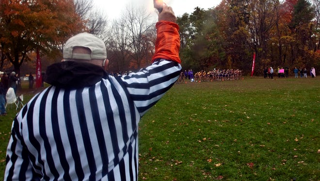 Referee Mel Heimark fires his gun to start the South Milwaukee cross country sectional in 2010. The WIAA is pleading parents and fans in the crowd to do less yelling at officials and give more verbal support toward their children and teams.
