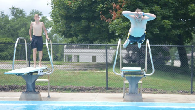 Kaleb Doty, right, leaps into the dive pool Saturday, July 11, at Bouws Pool while his friend Cameron Kron watches.
