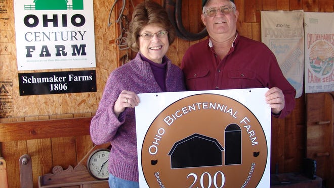 Wendy and Jim Schumaker pose with their ODA farm recognition signs.