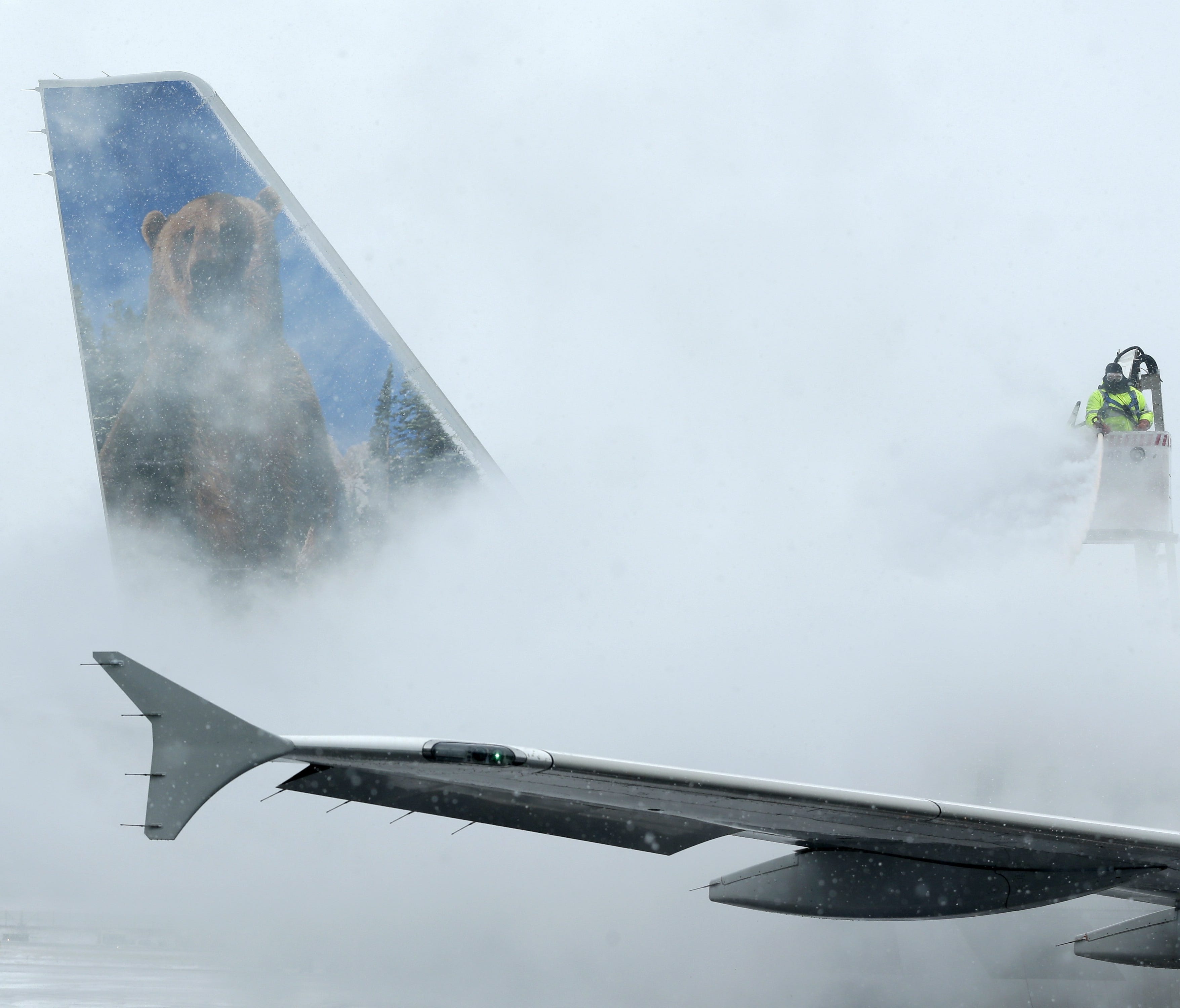 This file photo from Jan. 26, 2015, shows a crewmember de-icing a Frontier Airlines plane at LaGuardia Airport in New York.