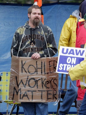 A striking UAW Local 833 member stands with a home made sign on the picket line Tuesday November 17, 2015 in Kohler.