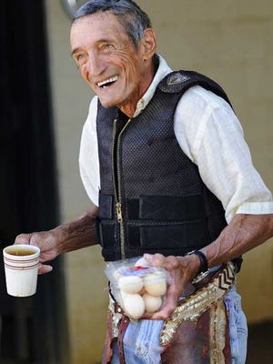 'Cowboy' Jones heads to his Cadillac with a cup of coffee and a dozen farm-fresh eggs he was given by a trainer at Ellis Park. Jones joked that he was willing to ride for money or eggs after his morning horse work in 2011.