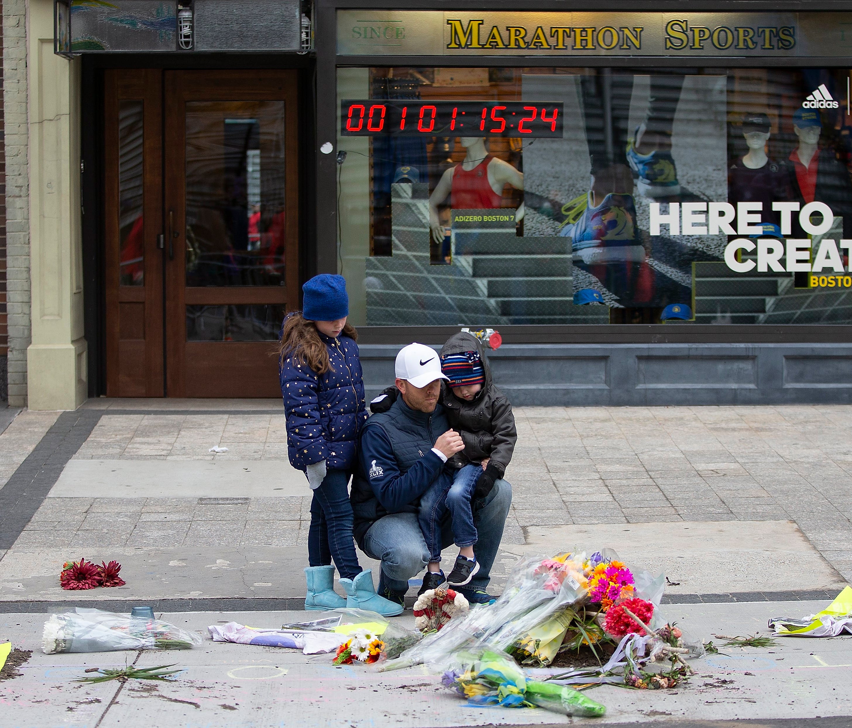 People pause at a memorial on the ground outside of at Marathon Sports at 671 Boylston St., the location of the first explosion, following a memorial ceremony on the fifth anniversary of the Boston Marathon Bombing, n Boston, Mass. on April 15, 2018.