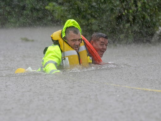 Wilford Martinez, right, is rescued from his flooded