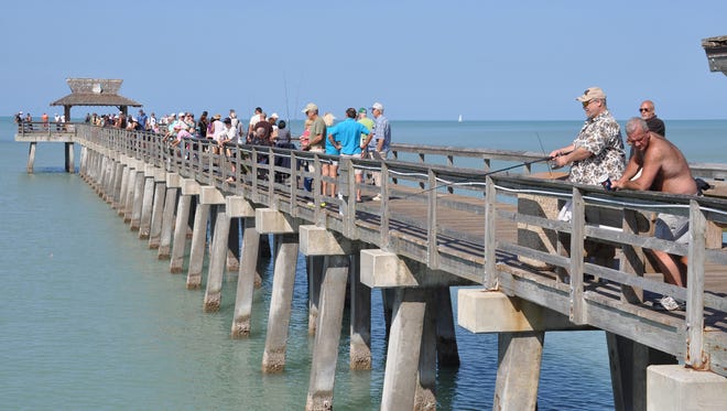 Dozens of people line the Naples Pier to fish in this file photo.