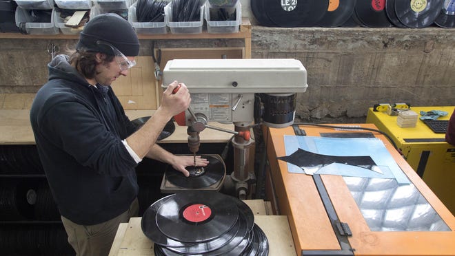 George Kamen uses a drill press to prepare records before they are made into decorative clocks at Wrecords By Monkey in Brooklyn, New York. The company cuts and shapes the lacquered discs into jewelry, clocks, wall art and other novelties.