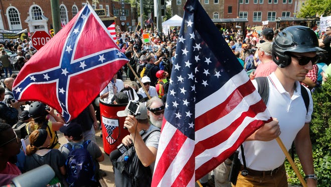 White nationalist demonstrators walk into Lee park surrounded by counter demonstrators in Charlottesville, Va., Saturday, Aug. 12, 2017. Gov. Terry McAuliffe declared a state of emergency and police dressed in riot gear ordered people to disperse after chaotic violent clashes between white nationalists and counter protestors. (AP Photo/Steve Helber)