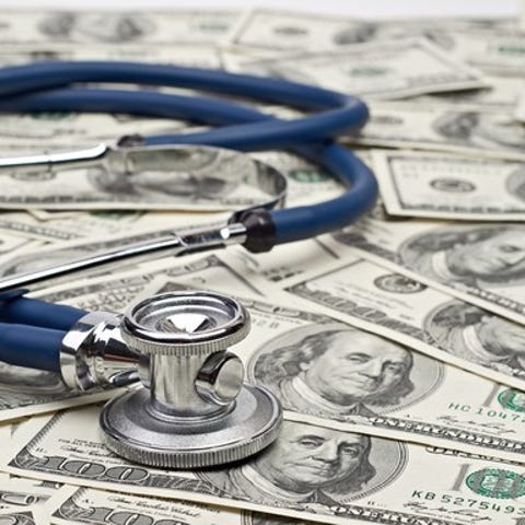 A stethoscope sitting on a bed of $100 bills