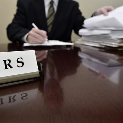 An IRS agent examining paper tax filings at his...