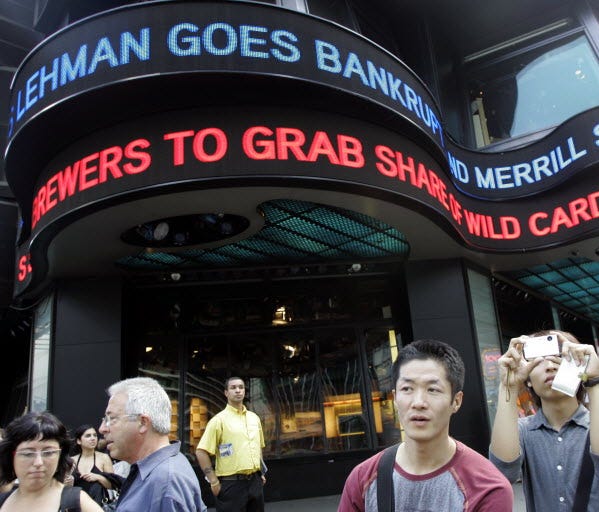 In this Sept. 15, 2008, tourists take pictures in New York's Times Square as the days financial news about the bankruptcy of Lehman Brothers is displayed on the ABC news ticker.