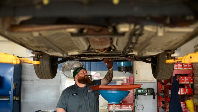 Jason LeSage works on changing the oil to a vehicle inside the garage at Auto Aces, W. Mason St., in Green Bay on March 10.