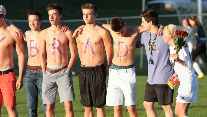 As classmates proudly show off their painted message, Darby McKernan, far right, appears to point out that their message is displayed exactly backward for viewing of the fans in the stands.