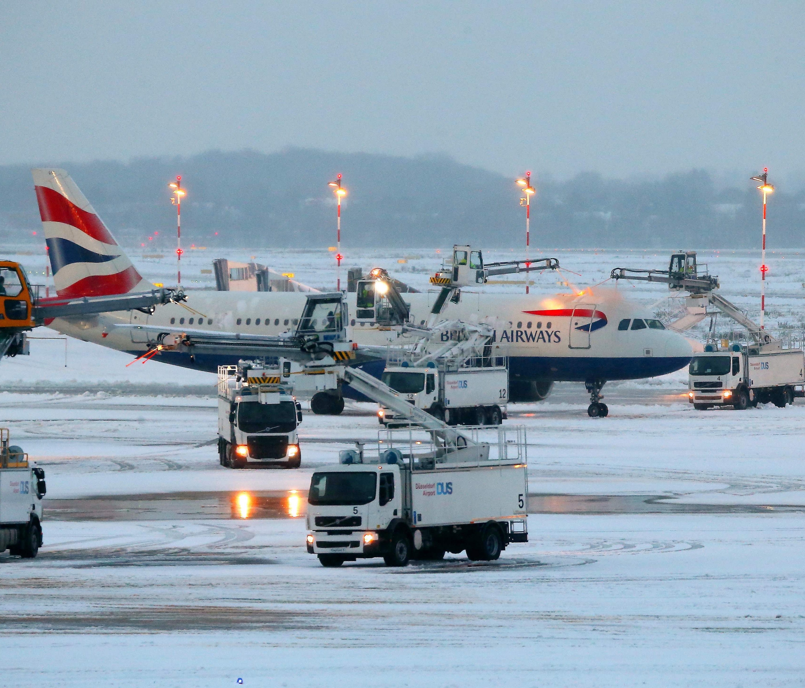 A British Airways jet is being de-iced at the airport in Dusseldorf, Germany, on Dec. 10, 2017.  Due to the weather conditions, Duesseldorf airport was forced to close for four hours during the afternoon, news agency DPA reported. / AFP PHOTO / dpa / 