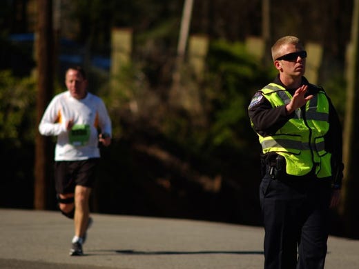 Knox City Police Cadet, Calvin Clabo, stops traffic for runners at the intersection of North Broadway, West Jackson, World's Fair Park Dr. and Oak Ave., during the 2016 Covenant Health Knoxville Marathon on Sunday, April 3, 2016. 