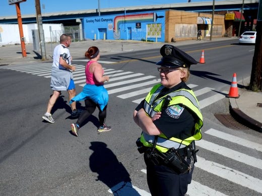 Shawn Millsaps/Special to News Sentinel Knoxville Police Department Officer Patty Tipton controls traffic at North Broadway and West Depot as runners pass by during the 2016 Covenant Health Knoxville Marathon on April 3. Foot races are now one of the major employers of off-duty police.
