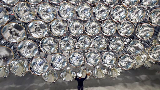 In this March 21, 2017 photo engineer Volkmar Dohmen stands in front of xenon short-arc lamps in the DLR German national aeronautics and space research center in Juelich, western Germany. The lights are part of an artificial sun that will be used for research purposes.  (Caroline Seidel/dpa via AP)