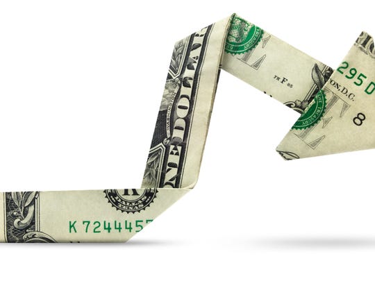 A dollar bill folded origami-style into an arrow pointing downward.