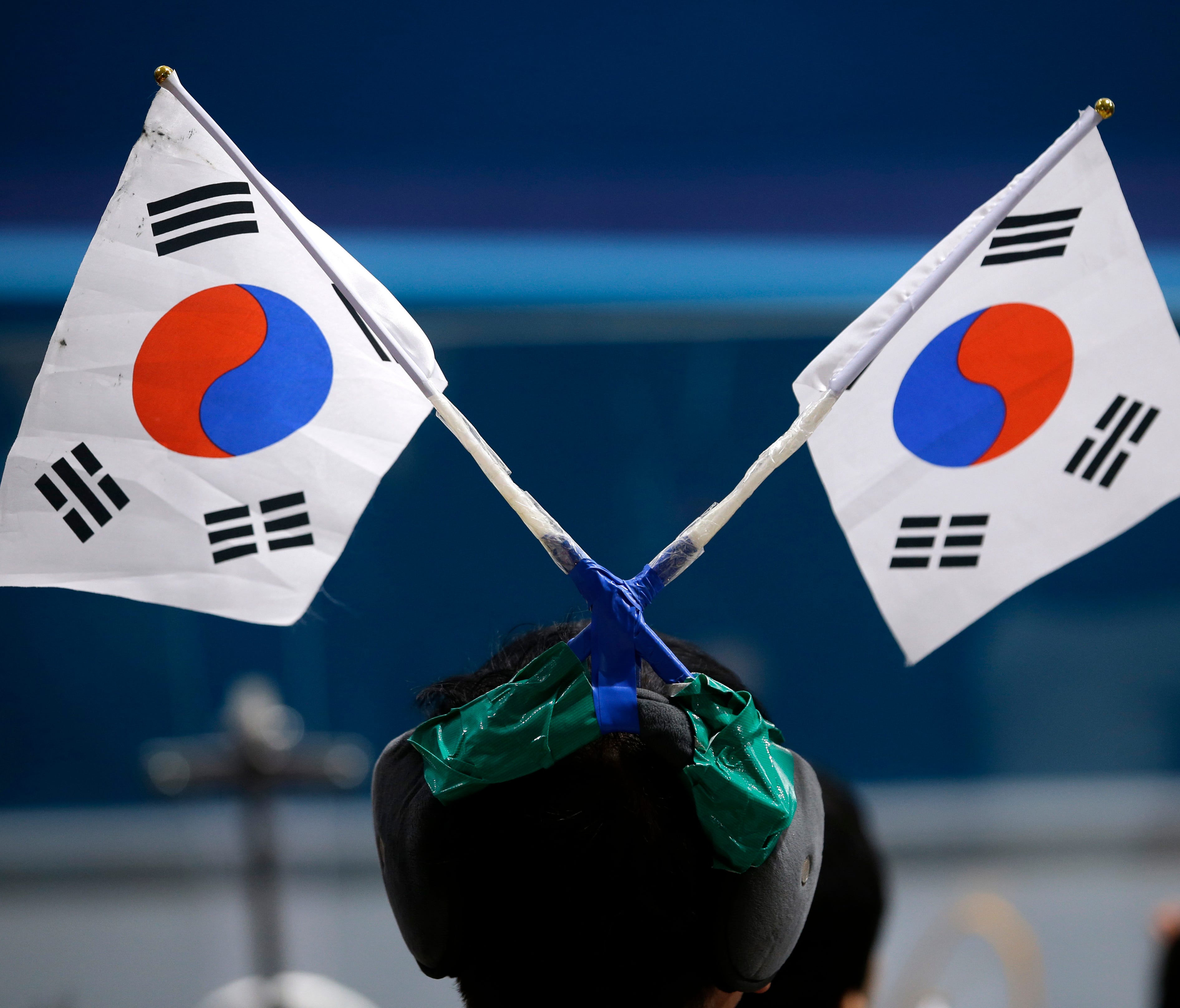 South Korea is hosting the Winter Olympics this year. Here, a spectator straps Korean flags on his headwear as he watches the men's curling matches. The number of South Koreans traveling to the USA has increased significantly.