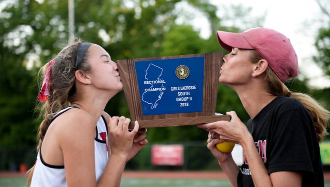 Haddonfield head coach Jessica Blake, right, and her daughter Mckenzie Blake kiss a South Group II trophy after defeating Camden Catholic 18-7 Thursday, May 24, 2018 in Haddonfield, N.J.