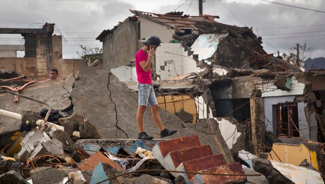 A man talks on his cell while searching for belongings amid the rubble of his home destroyed by Hurricane Matthew in Baracoa, Cuba, Wednesday, Oct. 5, 2016. The hurricane rolled across the sparsely populated tip of Cuba overnight, destroying dozens of homes in Cuba's easternmost city, Baracoa, leaving hundreds of others damaged.