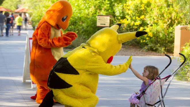 Pikachu and Charmander greet Phoebe Hills, 2, of Tempe, at the Phoenix Zoo on Saturday, July 23, 2016.