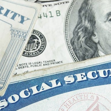 Two Social Security cards partially covering a hundred dollar bill.