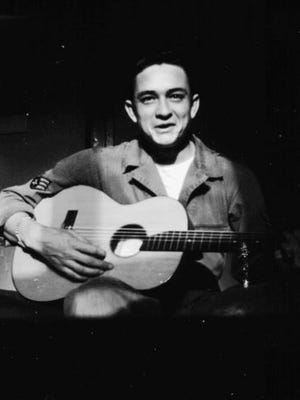 Johnny Cash holds his $10 guitar. He sold appliances door to door before auditioning for and signing with Sam Phillips at Sun Records in Memphis, Tenn.