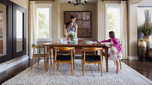 Mother and daughter setting table in dining room