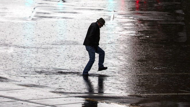 A man crosses a large puddle as El Nino hits downtown Phoenix near city scape on Jan. 7, 2016 in Phoenix, Ariz.