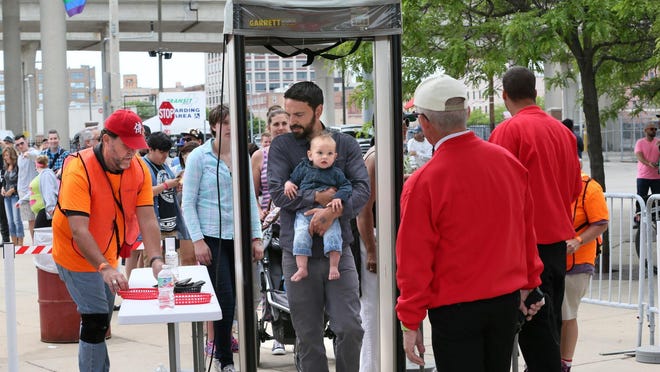 Andy Krieger of New Berlin, holding his one-year-old son Francis Krieger, goes through the metal detectors at the entry to Pridefest on the Summerfest grounds.