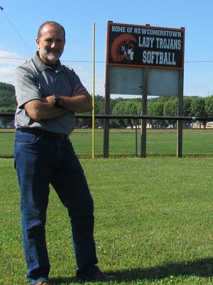 Charles Lenzo of Lenzo Studio Photography of Newcomerstown is pictured in front of a new sign that he purchased to help promote the Lady Trojans softball team.