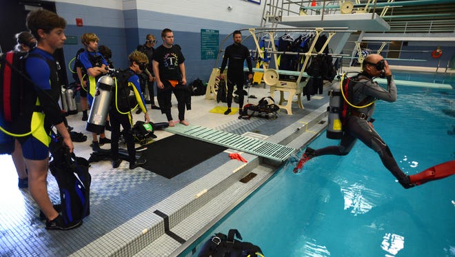 Kent Rychel, right, co-owner and scuba instructor for the Colorado Scuba Diving Academy, shows Polaris Expeditionary Learning school students, how to properly step into the water, during a scuba diving class at Edora Pool Ice Center Tuesday Sept. 23, 2014. Twenty students will gain scuba certification through the Colorado Scuba Diving Academy this fall and do community serve in February. In May, they will travel to the Florida Keys to assist with coral restoration wi the Coral Restoration Foundation.