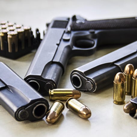 Three pistols laying on table with bullets