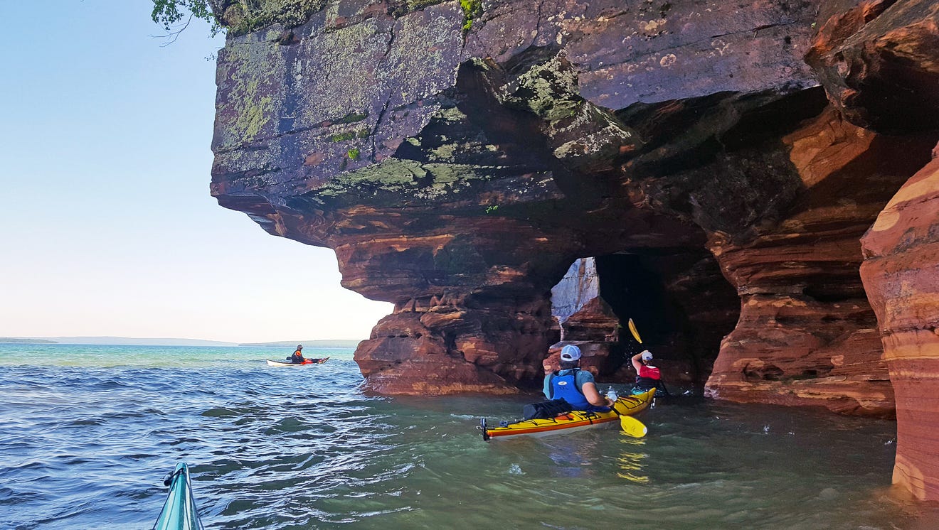 Los kayakistas reman a través de las cuevas marinas en la Isla de la Arena en la Costa Nacional de las Islas Apóstoles.