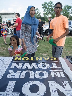 Aamina Ahmed, 5-year-old Aasiya Syed and 14-year-old Talha Syed sign a banner to stop hate and promote safe communities.