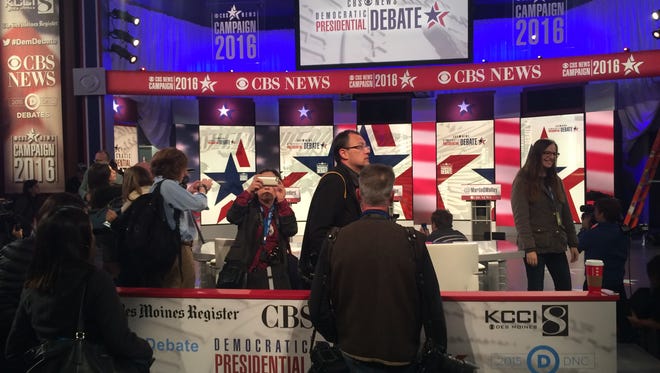Journalists take pictures of an empty stage and the backdrop of the Democratic Debate at Drake Saturday morning.