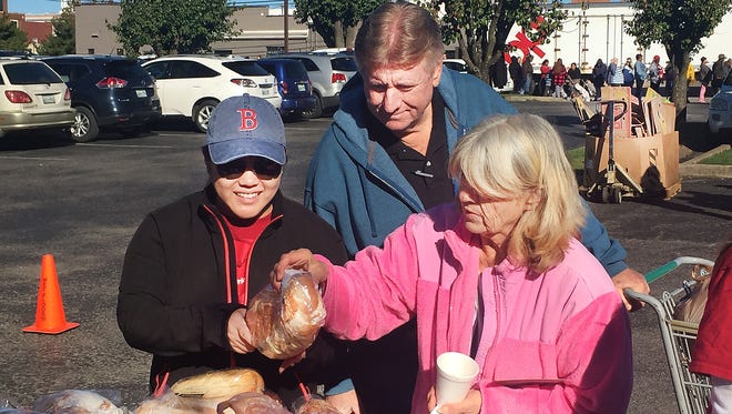 Volunteers Cathy Phillips, left, and Gary Evans, center, help Judy Fleming at a previous mobile food pantry.