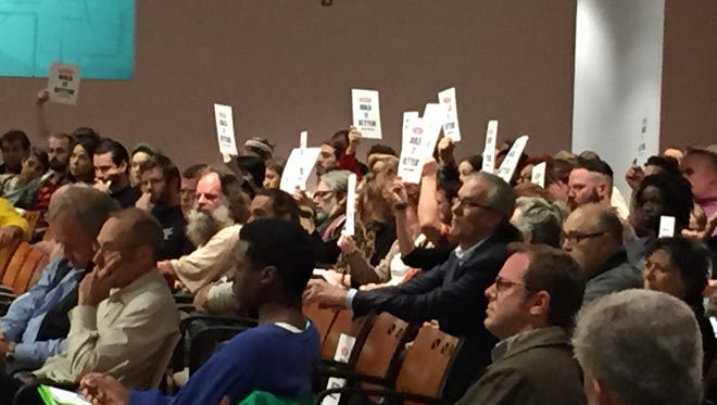 Dozens of residents from the All Saints neighborhood hold up "Build it Better" signs, a reference to the neighborhood's ardent opposition to a $2-million city land deal.