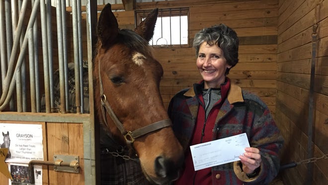 Carol Bascome, Director of the Hoofbeats Therapeutic Riding Center, receives a $1,200 check from the Gannett Foundation for help with the upcoming Special Olympics. Also pictured is Herme, a therapeutic riding horse at the center.
