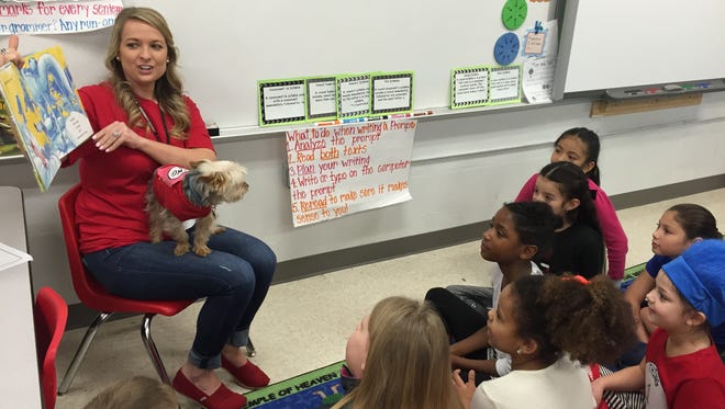 School psychologist Tara Bowker with her dog, Cash, reads to students at Hobgood Elementary School as part of Read Across America Day on Friday morning.
