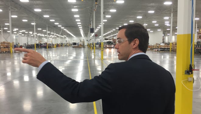 Proterra CEO Ryan Popple points to a bus on the company's factory floor in Greenville Thursday.