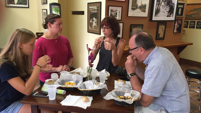 Capital City Food Tours guide Brittany Hammer (second from left) sits with a tour group at Gotham Bagels in Madison.