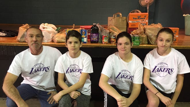 Lakers coach Steve Frigerio and players Emilio Licea, Jillian Hayward and Georgia Cork with some of the food they collected for the Garden City Food Bank.
