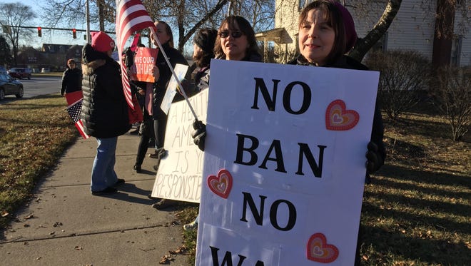 Okemos resident Joanne Guertin, right, and Lansing resident Katherine Erickson, middle, were among dozens of protesters who lined the sidewalk in front of U.S. Rep Mike Bishop's Brighton office on Feb. 13.