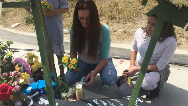 San Bernardino resident Sue Howell and her 11-year-old granddaughter, Jasmin Romero, and 9-year-old grandson, Andrew Romero, contribute to the memorial outside North Park Elementary School on Tuesday.