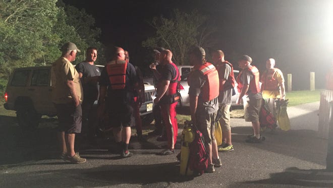 Downe Township Dive Team members talk with investigators and firefighters as they prepare to recover two bodies from South Vineland Park Lake Wednesday night.